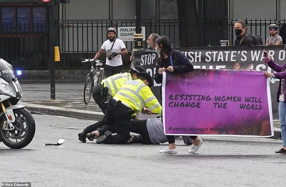 The man is detained by police officers following the dramatic incident outside the Houses of Parliament this afternoon