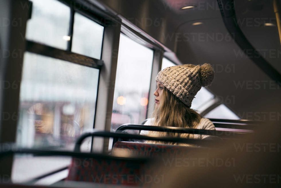 thoughtful woman looking through window while traveling in bus CAVF38268