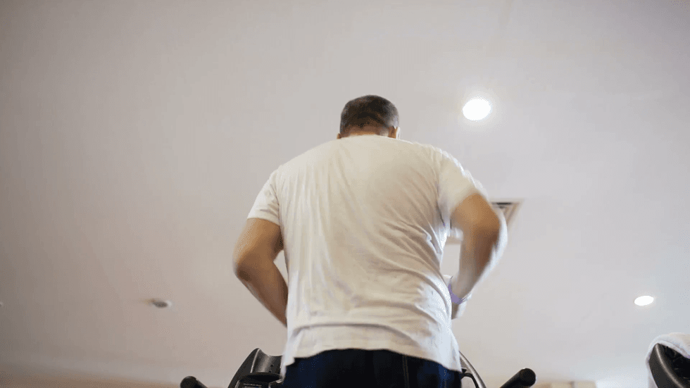tilt shot of 50 years old man running on the treadmill back view with focus on the feet at the end low angle shot 7jdmm7tb F0000