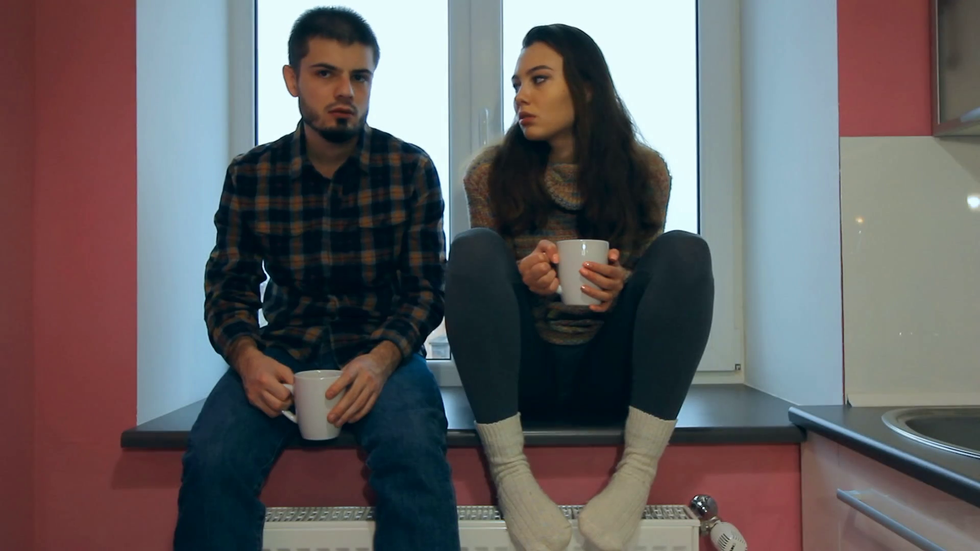tired couple sitting on the windowsill and drinking a coffee unhap