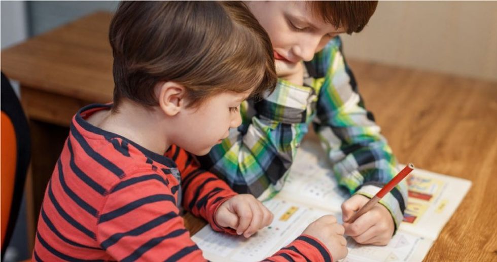 Two young boys doing school work together