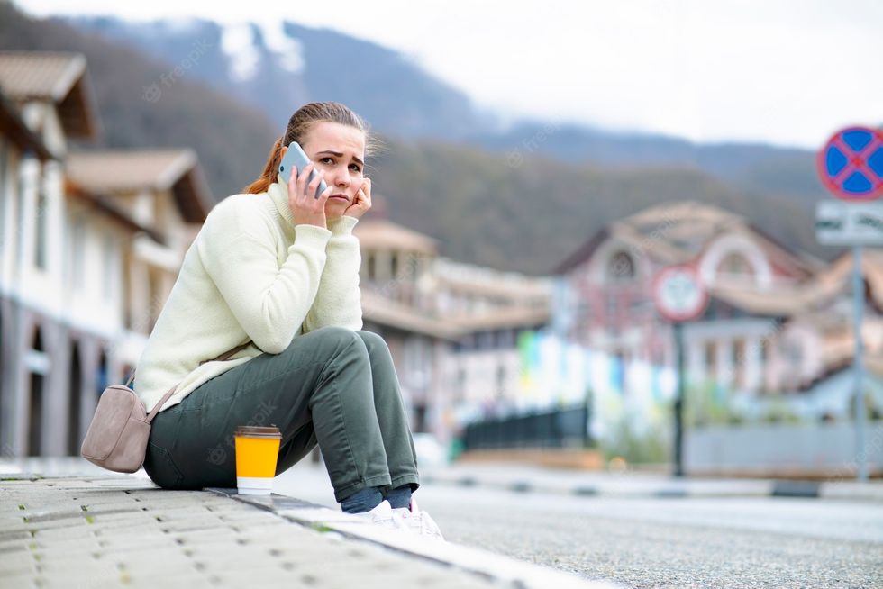 unhappy sad woman speaks cell phone girl sitting sidewalk side road talking smartphone 228441 283