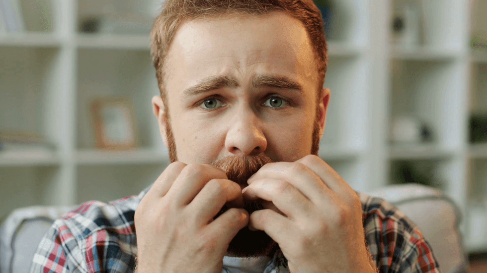 videoblocks portrait of man in stress sitting on the sofa at home in the living room and biting his nails because he feeling fear close up rub8cjjm thumbnail full01