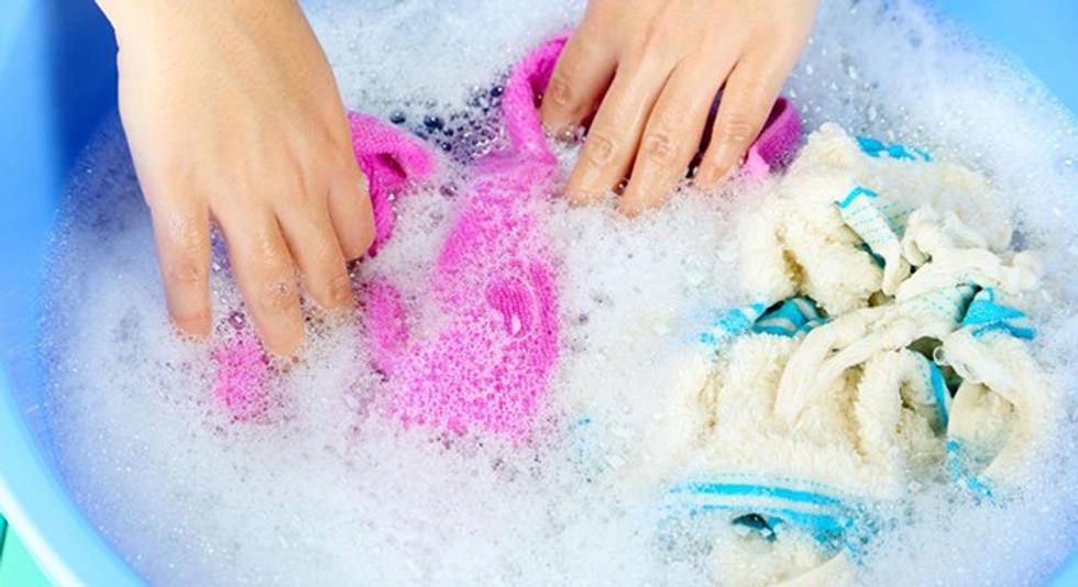 washing garments in soapy water in blue tub
