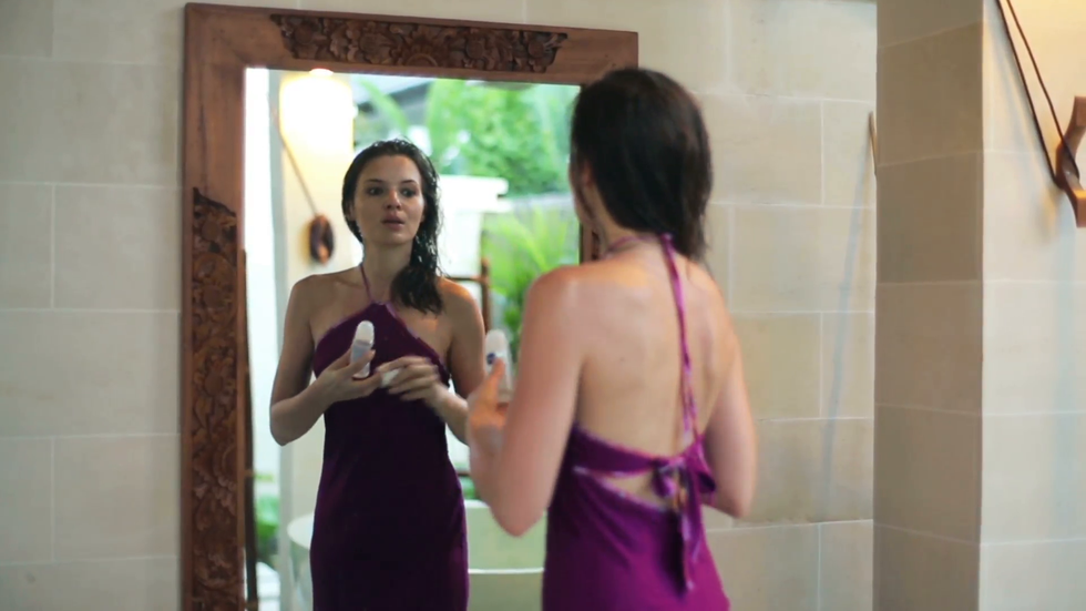 woman applying antiperspirant deodorant in front of the mirror njuhfkerjl F0000