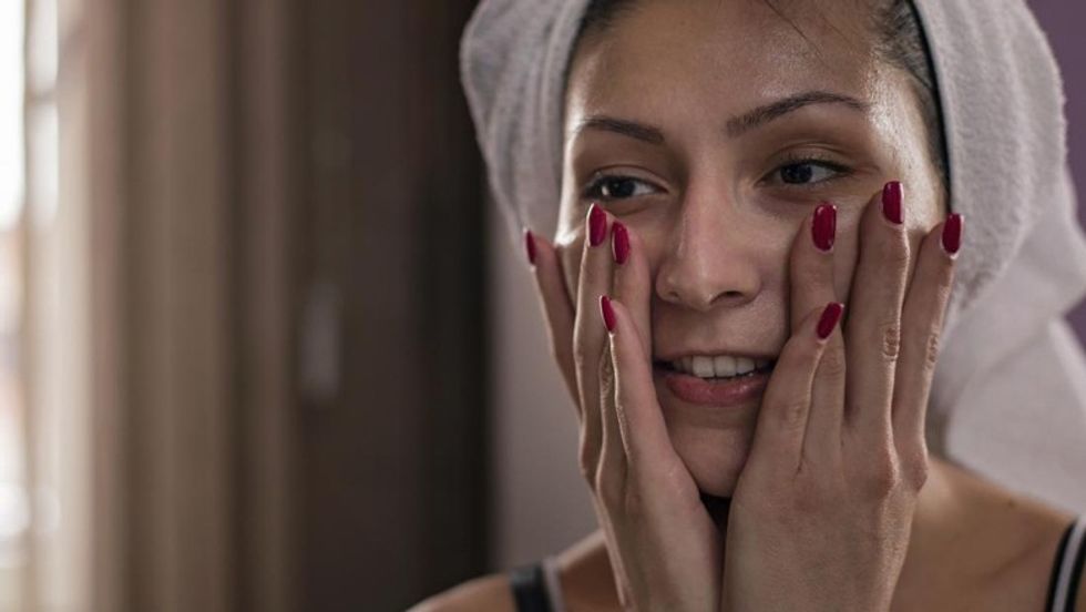 woman applying cosmetic products to skin on face