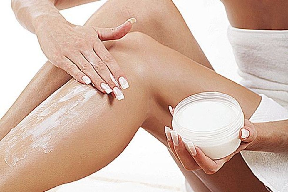 Woman applying moisturiser to her legs