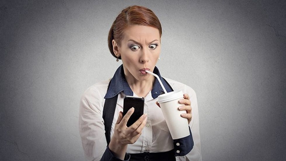 woman drinking soda while looking at phone fb