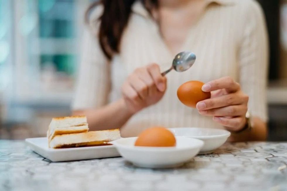 Woman eating egg e1653902536377