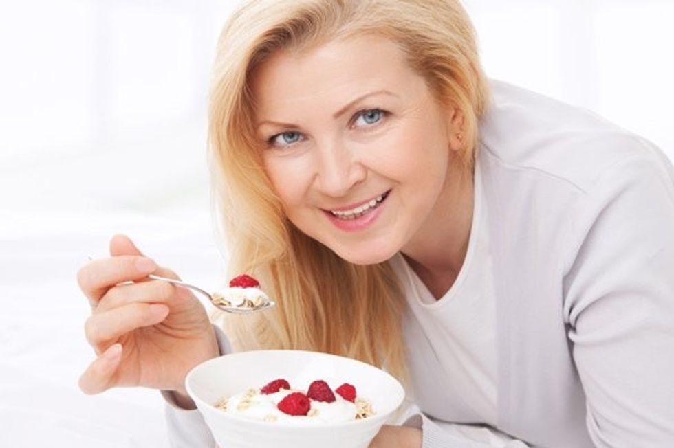 woman eating yogurt with berries flax cwgpjl