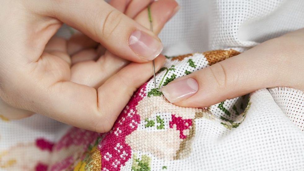 Woman hands doing cross-stitch. A close up of embroidery.