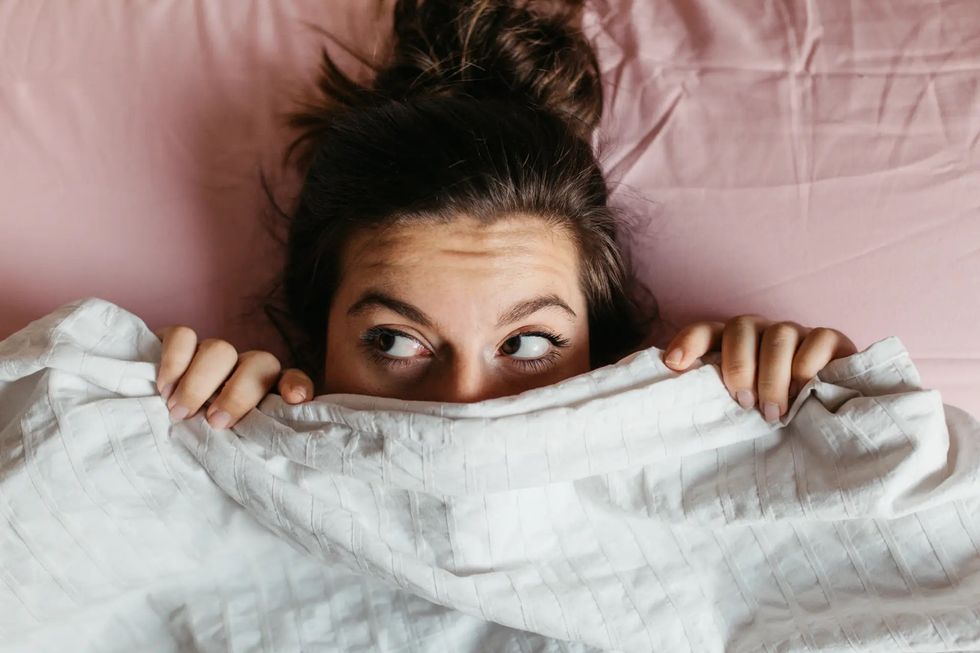 woman hiding under covers odor