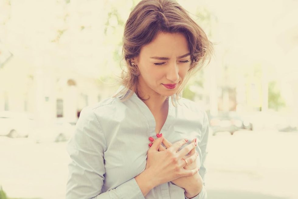 woman holding her chest with a possible heart attack