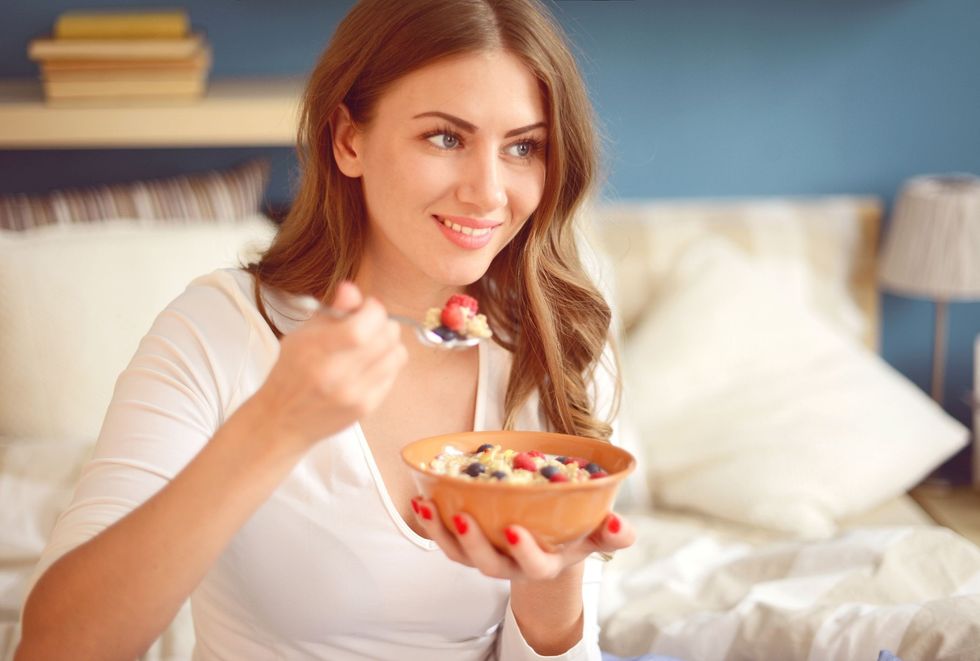 woman in pajamas in bedroom eating muesli with royalty free image 525343946 1566830366