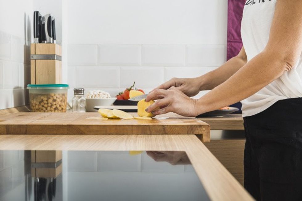woman standing at kitchen cutting potatoes 23 2147810090