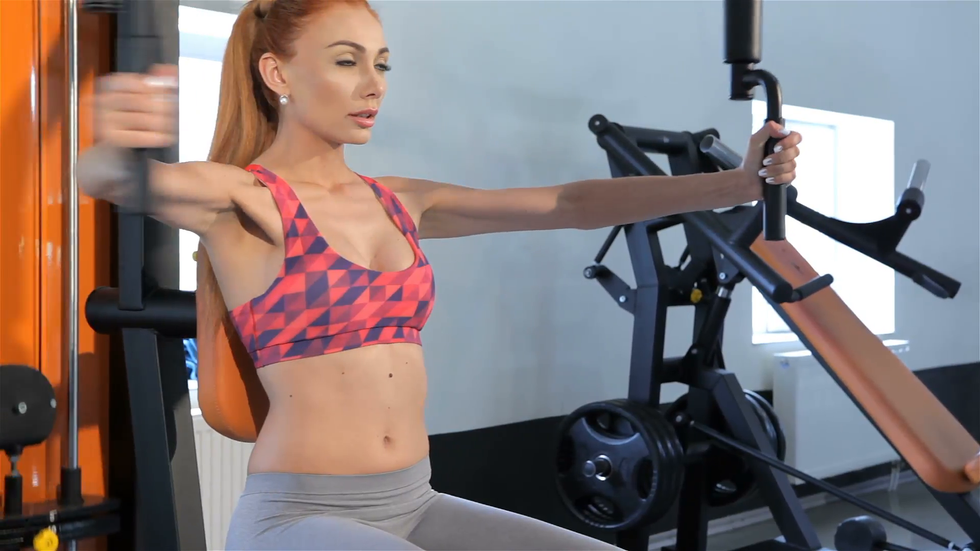 woman trains her chest muscles on pec deck machine at the fitness centre rkifi1bd F0000