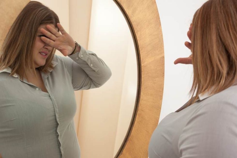 woman unhappy with weight in mirror. q67 crop smart