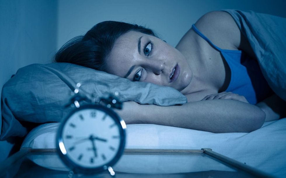 woman wide awake looking at alarm clock
