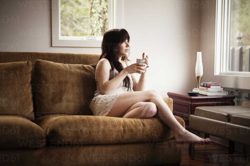woman with coffee cup relaxing on sofa CAVF09960