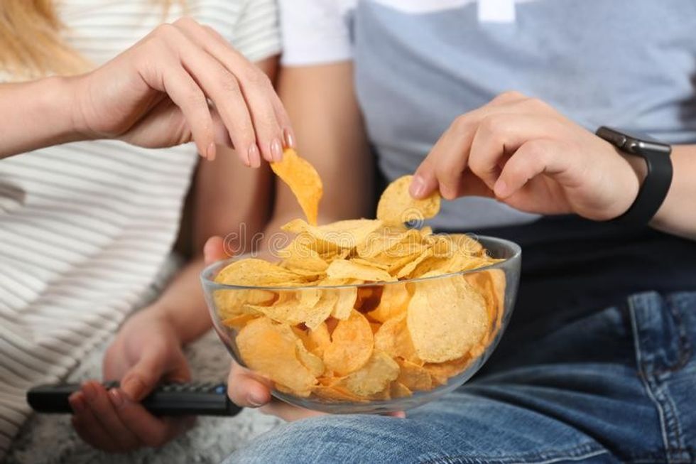 young couple eating chips watching tv closeup view 136326330