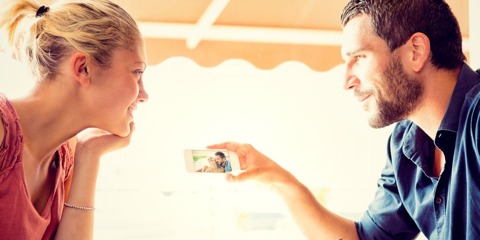 Young couple watching photos at italian café