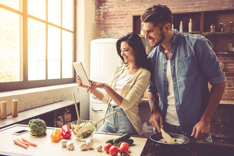 young happy couple cooking in kitchen