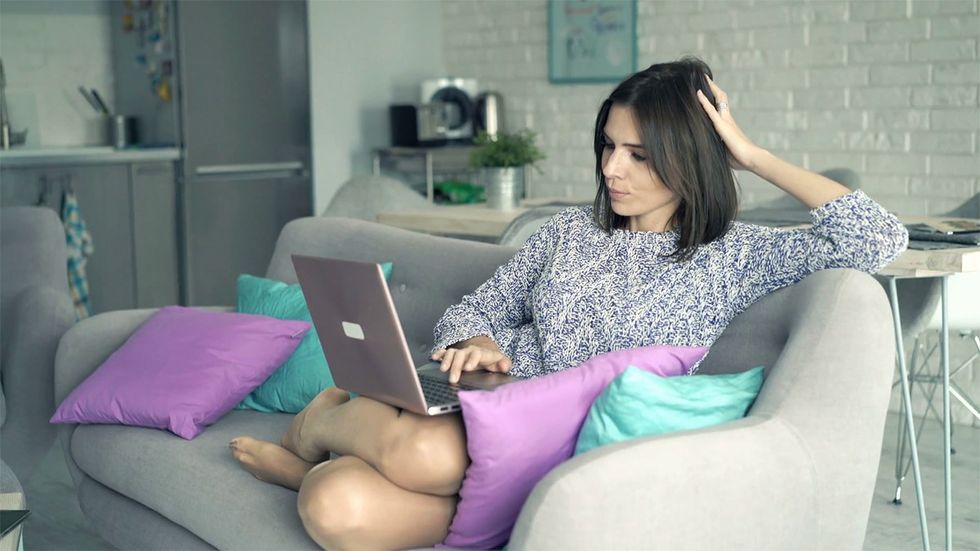 young happy woman watching movie on laptop while relaxing on sofa