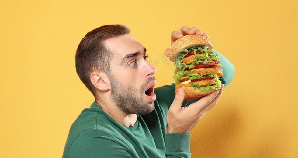 young hungry man eating huge