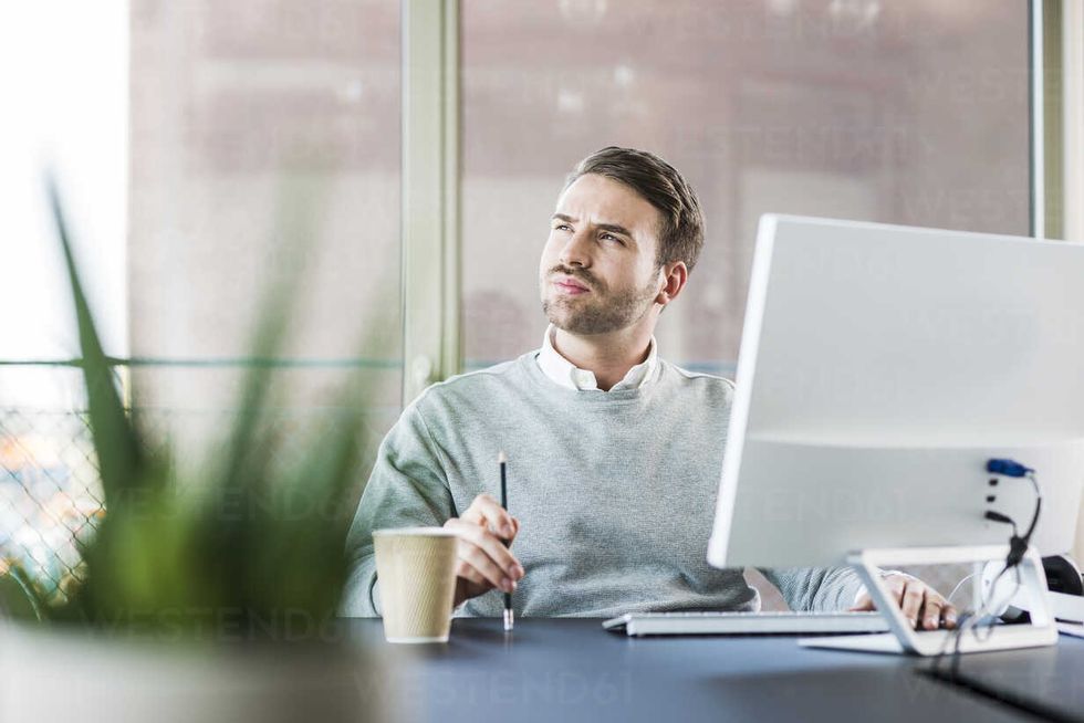 young man at office desk thinking UUF007025