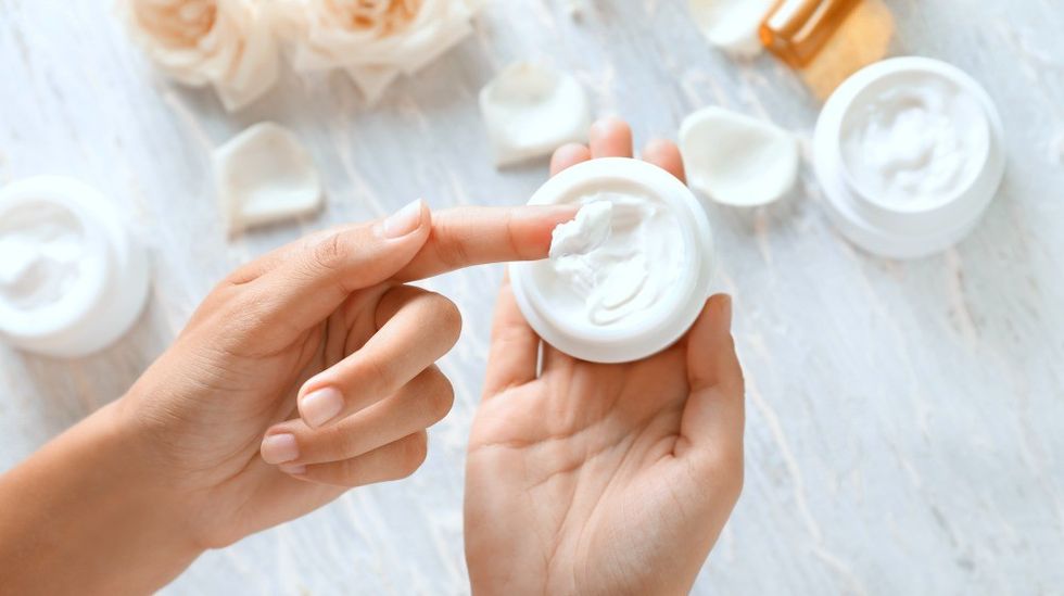 young woman applying body cream closeup dry skin in winter ss Featured