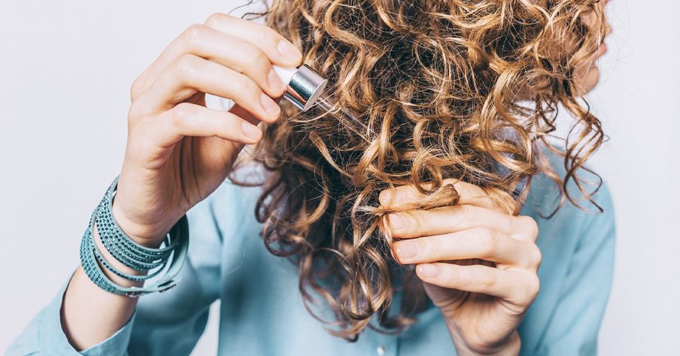 Young woman in blue shirt holding her curly hair tips facebook
