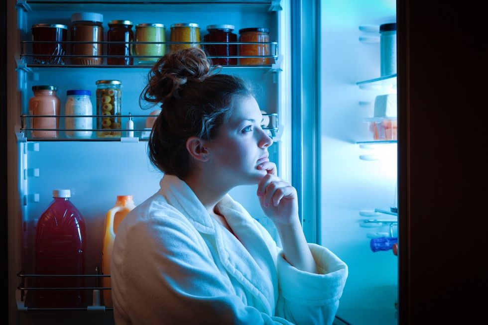 young woman in front of fridge at night
