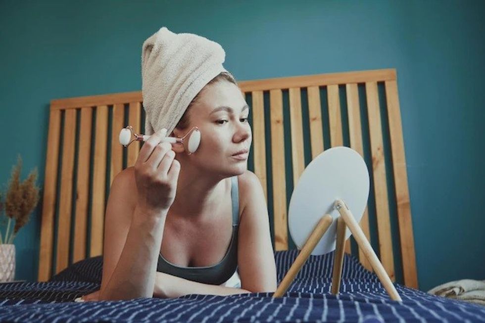 young woman using jade facial roller face massage