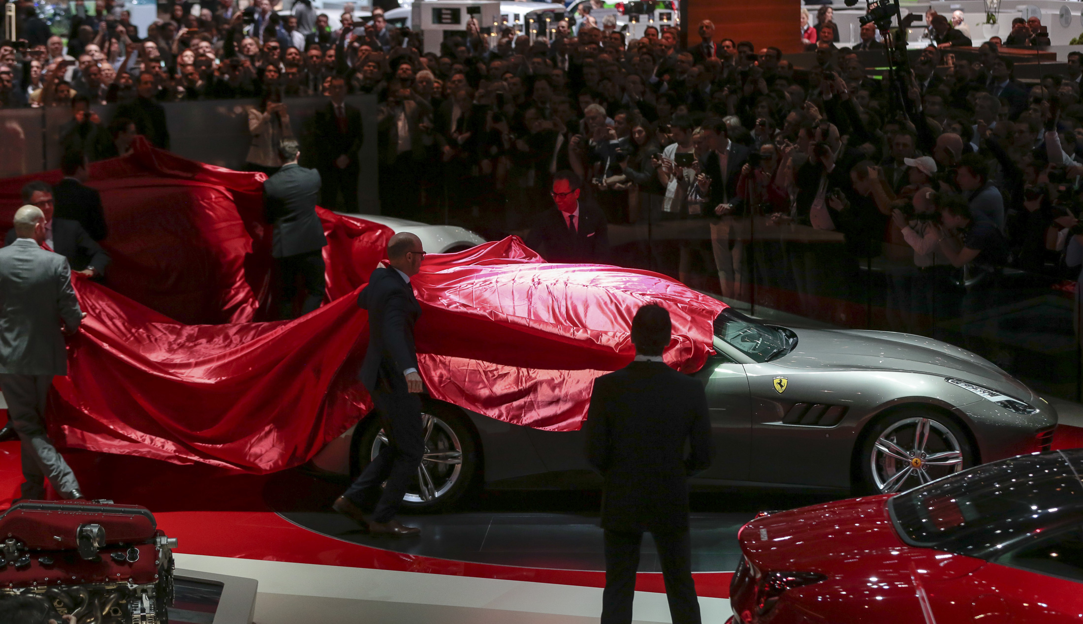 Workers remove the covers from a Ferrari GTC4 Lusso automobile, produced by Ferrari SpA, on the first day of the 86th Geneva International Motor Show in Geneva, Switzerland on Tuesday, March 1, 2016. The show opens to the public on March 3, and will showcase the latest models from the world's top automakers. Photographer: Jason Alden/Bloomberg