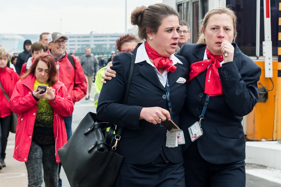 People react as they walk away from Brussels airport after explosions rocked the facility in Brussels, Belgium Tuesday March 22, 2016.   Explosions rocked the Brussels airport and the subway system Tuesday, just days after the main suspect in the November Paris attacks was arrested in the city, police said. (AP Photo/Geert Vanden Wijngaert)