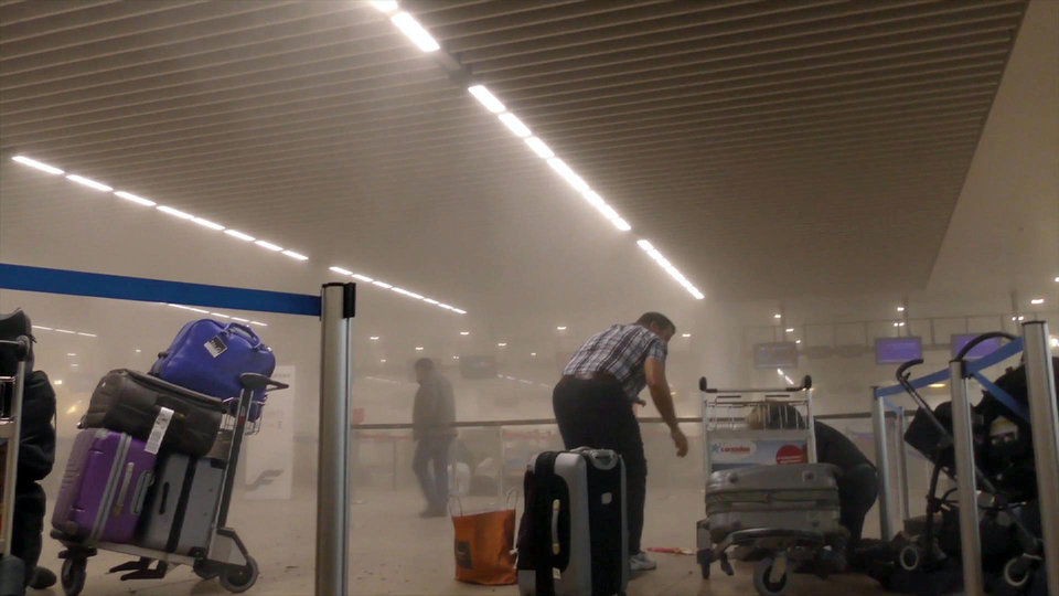 In this photo provided by Ralph Usbeck an unidentified traveller gets to his feet in a smoke filled terminal at Brussels Airport, in Brussels after explosions Tuesday, March 22, 2016. Authorities locked down the Belgian capital on Tuesday after explosions rocked the Brussels airport and subway system, killing  a number of people and injuring many more. Belgium raised its terror alert to its highest level, diverting arriving planes and trains and ordering people to stay where they were. Airports across Europe tightened security.  (Ralph Usbeck via AP)
