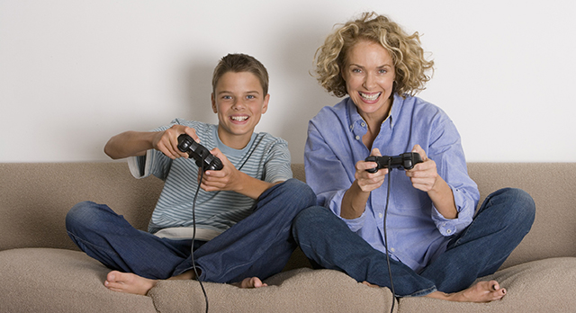 Mother and son (13-15) playing with game controls, smiling