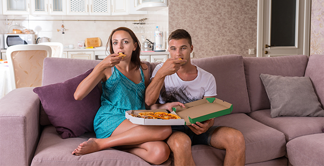 Young Couple Watching Television and Eating Pizza