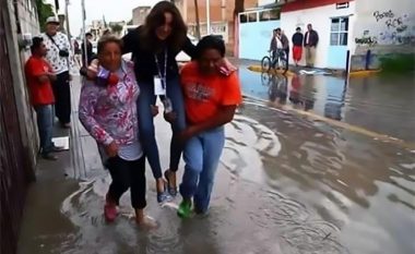 Për t’i ruajtur këpucët e shtrenjta, gazetarja bartet nga viktimat e përmbytjes (Foto)