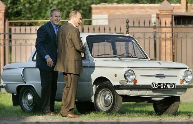 US President Bush and Russian President Putin stand near Putin's first car before social dinner in Stralna...U.S. President George W. Bush (L) and Russian President Vladimir Putin look at Putin's first car, a Zaporozhets, before a social dinner on the grounds of the Konstantinovsky Palace in Stralna, Russia, July 14, 2006. REUTERS/Jason Reed (RUSSIA)