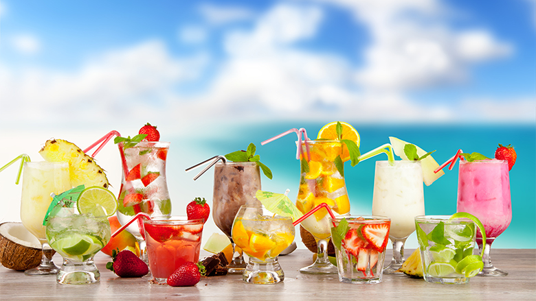 Summer cocktails with pieces of fruit on wooden table. Blur beach on background