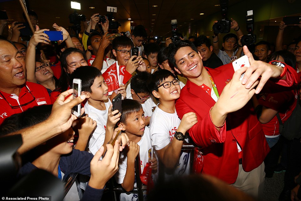 Singaporean swimmer Joseph Schooling, front right, poses for a photo with people at the Singapore Changi Airport in Singapore Monday, Aug. 15, 2016. Schooling won gold medal in the men's 100-meter butterfly and made history by winning the country's first gold medal at the 2016 Summer Olympics in Rio de Janeiro, Brazil. (AP Photo/Yong Teck Lim)