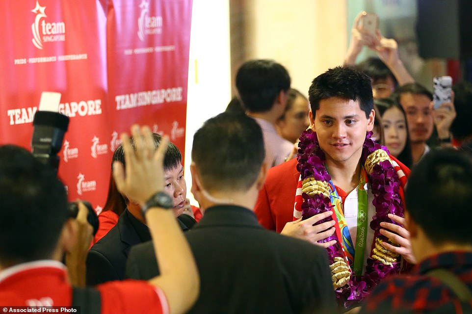 Singaporean swimmer Joseph Schooling is surrounded by media and people on his arrival at the Singapore Changi Airport in Singapore Monday, Aug. 15, 2016. Schooling won gold medal in the men's 100-meter butterfly and made history by winning the country's first gold medal at the 2016 Summer Olympics in Rio de Janeiro, Brazil. (AP Photo/Yong Teck Lim)