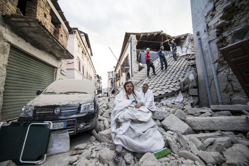 epaselect epa05508230 Residents look on as they stand on the rubble of collapsed buildings in Amatrice, central Italy, 24 August 2016, following a 6.2 magnitude earthquake, according to the United States Geological Survey (USGS), that struck at around 3:30 am local time (1:30 am GMT). The quake was felt across a broad section of central Italy, including the capital Rome where people in homes in the historic center felt a long swaying followed by aftershocks. According to reports at least 21 people died in the quake, 11 in Lazio and 10 in Marche regions. EPA/MASSIMO PERCOSSI