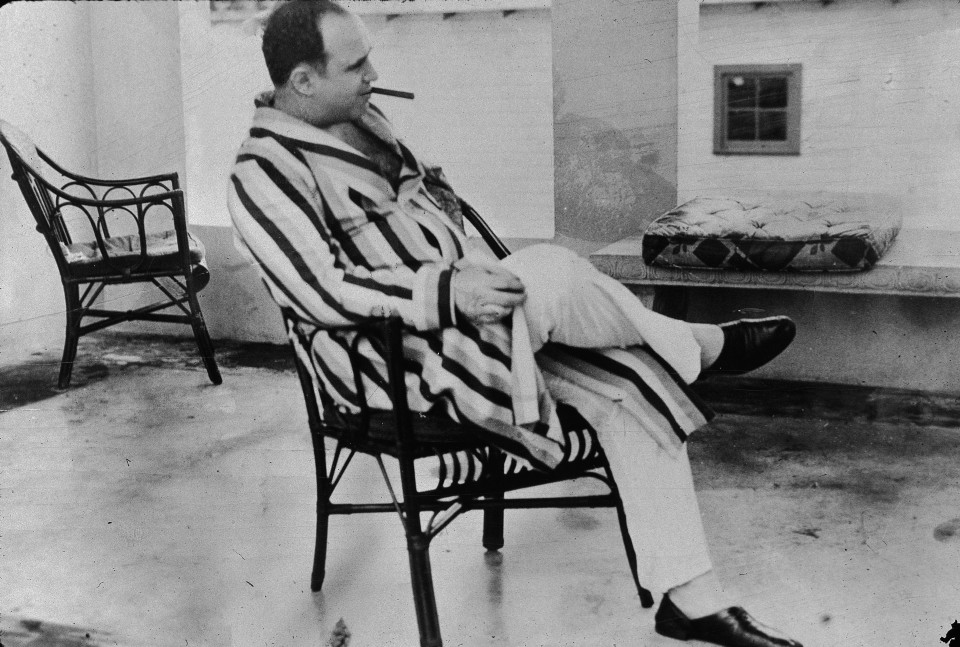 American gangster Al Capone ('Scarface') (1899 - 1947) relaxes in his vacation home, Miami, Florida, 1930. Capone smokes a cigar and wears a striped dressing gown and slippers. (Photo by New York Times/Getty Images)