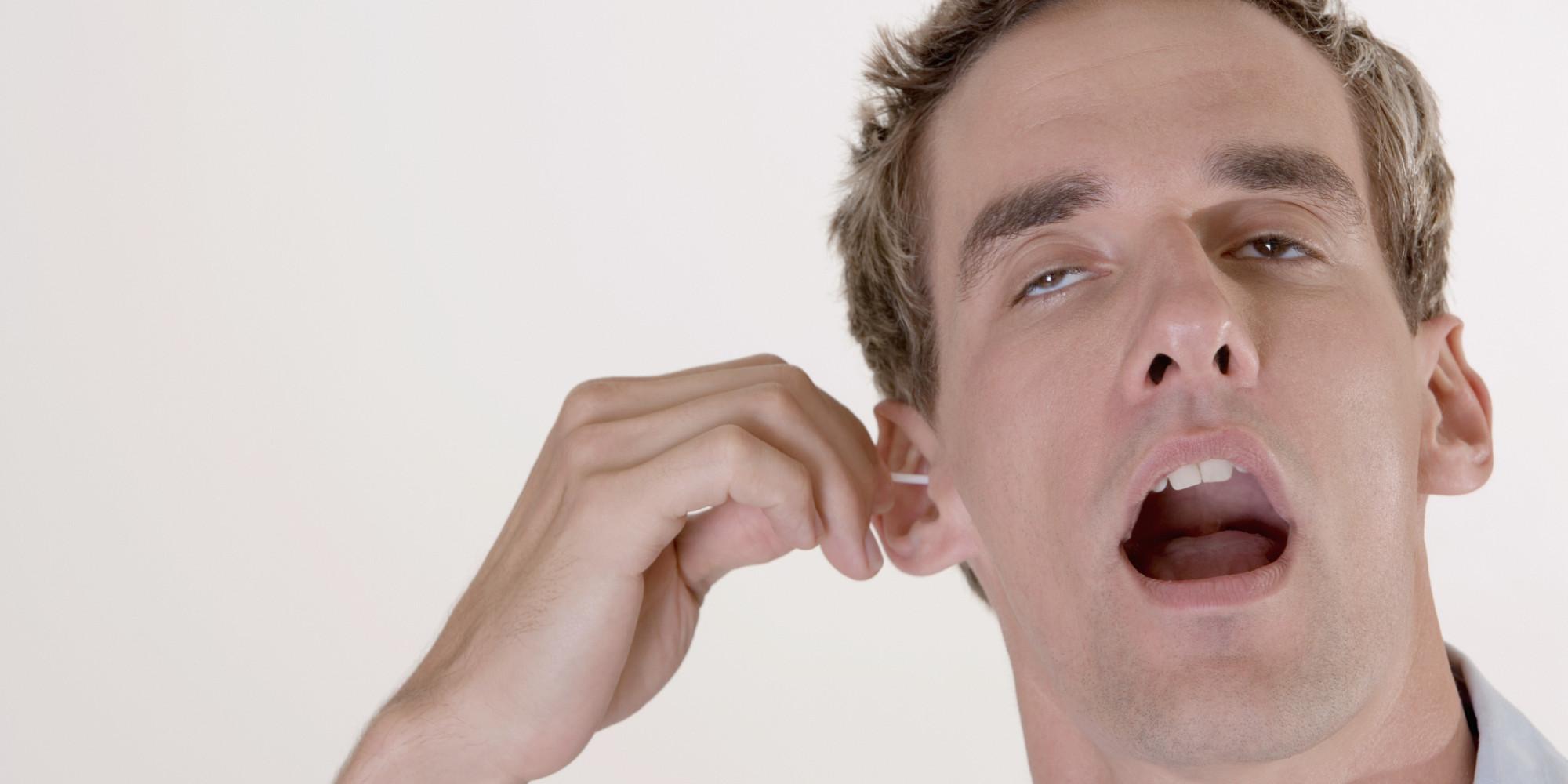 Close-up of a mid adult man cleaning his ear with a cotton swab