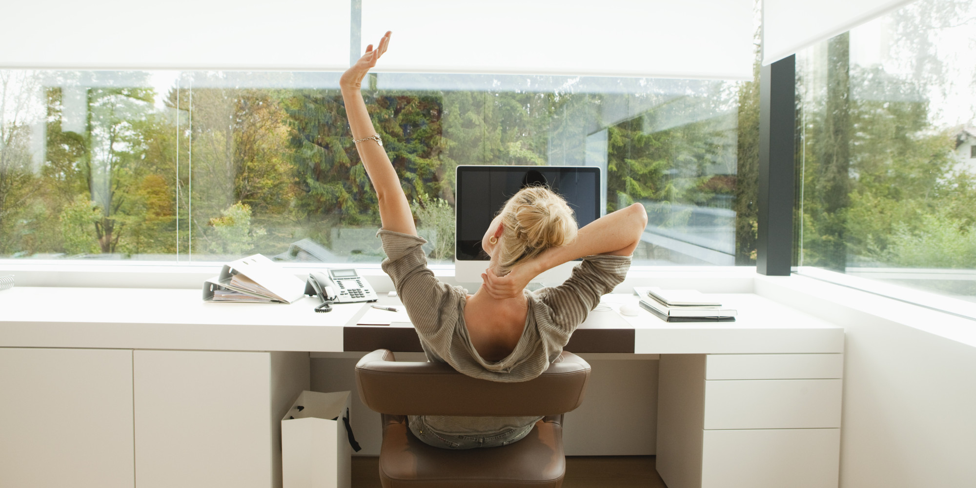 Young woman stretching at desk of office at home
