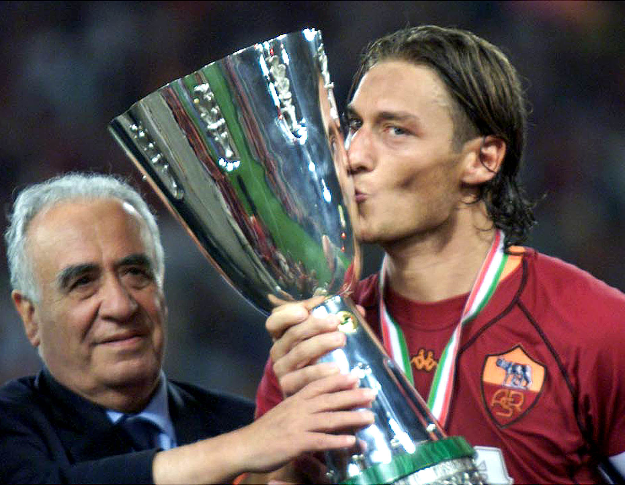 Il capitano Francesco Totti bacia la Supercoppa alla presenza del presidente della Roma, Franco Sensi, al termine della partita vinta per 3-0 contro la Fiorentina, in un'immagine del 19 agosto 2001. ANSA/FILIPPO MONTEFORTE