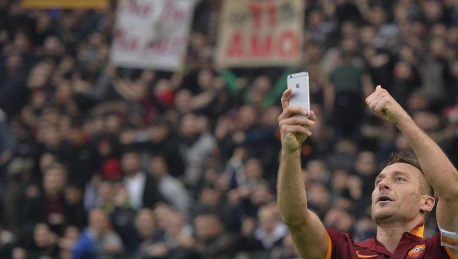 Roma's forward Francesco Totti celebrates by taking a "selfie" with fans after scoring a second goal during the Italian Serie A football match on January 11, 2015 at Rome's Olympic stadium. AFP PHOTO / ANDREAS SOLARO (Photo credit should read ANDREAS SOLARO/AFP/Getty Images)