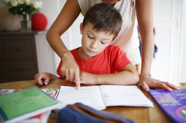 A 7 years old boy doing his homework with his mom